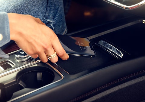 A smartphone is is being placed on the wireless charging pad in the front center console cubby. | Parks Lincoln of Gainesville in Gainesville FL